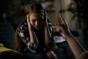 Upset girl covering ears during argument, showing need for calm conflict resolution